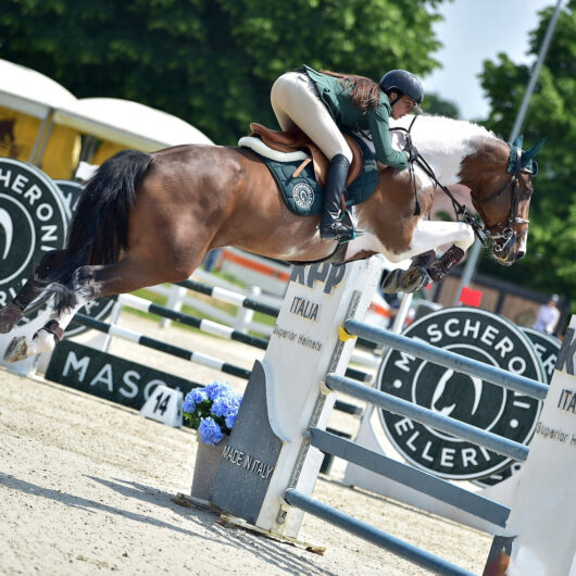 Michol mentre affronta un salto con il suo cavallo pezzato